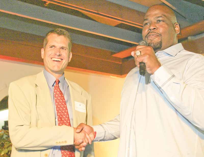 San Francisco 49ers head coach Jim Harbaugh, left, is introduced by former 49ers player Steve Wallace during the DeBartolo Scholarship banquet Monday at Leo’s Ristorante in Howland.