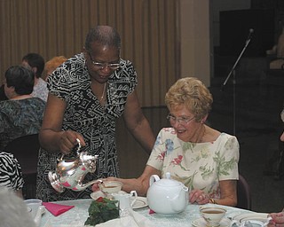 Jackie Burley, executive director of Protestant Family Service, who attended the Trinity UMW's tea, served the other guests at her table. Seated, from left, are Joanie Morrison of Austintown, Marilyn Morelli of Canfield and Elva Easton of Boardman.