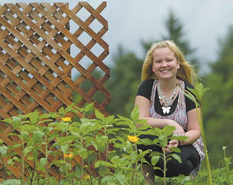 Tori Snyder, 17, one of the students in Kathleen Kromer’s Columbiana Educational Service Center class, is all smiles as she surveys sunflowers blooming in the Bloomin’ Butterfly Garden shaped like a butterfly at Goodness Grows ministry at Common Ground Church Community in Beaver Township. She wears a butterfly necklace to go with the garden theme. The garden features plants to attract birds, butterflies and bees.