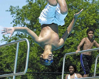 Raymond Sadler, 10, of Youngstown takes a flip from a diving board at North Side Pool on Belmont Avenue in Youngstown on Thursday. A chance of isolated thunderstorms forecast for the holiday weekend may put a slight damper on swimming.