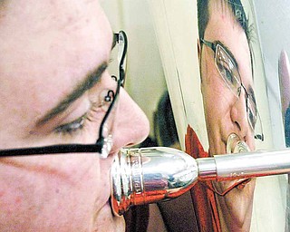 Tuba player Stephen Orlando is reflected in his horn as he rehearses with Girard Community Band. The band includes musicians of various ages and stages in their musical careers.