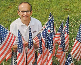 American flags surround Rich Suhovecky, who embraced a flag-planting project started by co-worker Karen Ament at Burgan Real Estate. Suhovecky coordinates the placement of 3,000 small U.S. flags at homes throughout Hubbard in the days leading up to July Fourth. He said he does it because he loves America and Hubbard.