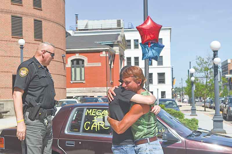 Frank Fordley hugs Richard McGrath’s, a Trumbull County Sheriff’s deputy, daughter, Megan, 16, outside the Trumbull County Sheriff’s Office on High Street in Warren as Richard McGrath looks at the car, a 1992 Dodge Spirit. Fordley runs a music store and car lot on Mahoning Avenue in Champion.