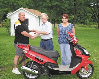 Fun in their future? Kiwanis Club of Western Mahoning County raffled off a street-legal scooter on June 22. Above is the winner of that raffle, Ken Frost, left, who took possession June 24. In the center is Dave Pinney, and at right is Frost’s wife, Holly.