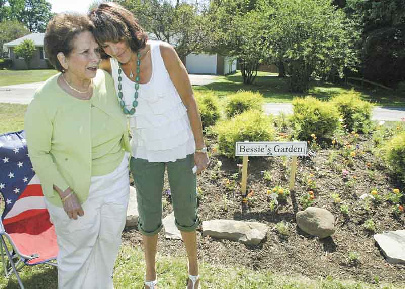 Bessie Anderson, left, is congratulated by Jodi Stoyak, Liberty Township trustee, during a dedication ceremony Friday at Anderson’s garden on Logan Way in Liberty. Anderson, a master gardener in Trumbull County, has created several gardens in the township over the past decade.