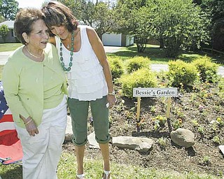 Bessie Anderson, left, is congratulated by Jodi Stoyak, Liberty Township trustee, during a dedication ceremony Friday at Anderson’s garden on Logan Way in Liberty. Anderson, a master gardener in Trumbull County, has created several gardens in the township over the past decade.