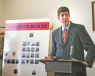 U.S. Attorney Steven M. Dettelbach stands near a poster of the 25 people wanted in a federal investigation into heroin sales in Youngstown. At a news conference Wednesday, he discussed federal and local law enforcement’s determination to press forward with aggressive pursuit of those distributing drugs and illegally carrying guns in the area.