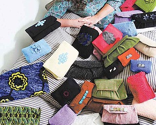In this photo taken June 16, Sinead Fyda poses with purses created by Tanzanian women in Hilliard, Ohio. Fyda lives in Tanzania up to eight months at a time while developing Jishike Social Couture, a business in which 21 women create handmade purses and bags that she sells when back in Columbus.