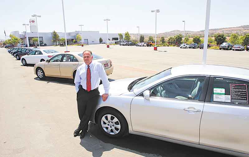 In this July 11, 2011 photo, Wayne B. Meyer, President of Sunroad Automotive in San Diego, leans on a car at his Chula Vista, Calif. dealership where a diminished inventory for small cars is evident in his near empty lot. (AP Photo/Lenny Ignelzi)