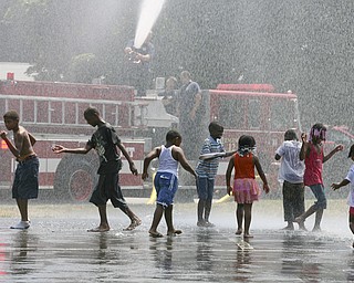 JESSICA M. KANALAS | THE VINDICATOR..Children from the Plaza View Apartments community cool off in water shot from the hose of Engine 12 of the Youngstown Fire Department. The firemen came out to teach the kids not to be afraid of the fire trucks they see on a daily basis. City Youth director Andrea Mahone runs summer activities for the children in the apartment complex, which is the only public housing in the city without a Youth Center. Mahone said the program, called "Increase the Peace," was implemented into the community to "make them respect and love the city of Youngstown."..-30-