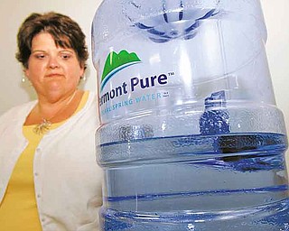 In this July 22, 2011 photo, Lori Girard-Pion stands by the water cooler at her state office in Colchester, Vt. Vermont state officials, who announced in March that they would pull the plug on water coolers and bottled water deliveries in state offices and buildings, are reconsidering the move amid a wave of complaints from workers. Calling bottled water a waste of taxpayer money, the state had said it hoped to save up to $200,000 annually by having workers use fountains and tap water instead. They said the change would help the environment, too, since toxic chemicals go into the making of plastic water bottles and ecologically-sensitive stream headwaters areas are damaged in the process of bottling. But many state workers have since complained that the tap water in their buildings is dirty or that they’ll have no way to get clean drinking water if the state stops buying bottled water for them. (AP Photo/Toby Talbot)