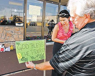 Forum Roller World owner Walt Hedrick and Julie Tam look at a sign left in front of the roller rink in Grand Prairie, Texas on Sunday, July 24, 2011, where police say a man gunned down four members of his estranged wife's family before fatally shooting himself at birthday party for his son Saturday night. (AP Photo/Richard W. Rodriguez)