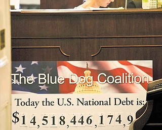 A staff member sits at a reception desk behind a national debt poster in the office of Rep. Jim Cooper, D-Tenn., Tuesday, July 26, 2011, in the Longworth House Office Building on Capitol Hill in Washington. (AP Photo/Harry Hamburg).