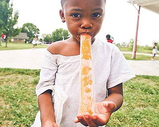 With part of his lunch still in hand, Kenny Byrd, 4, has dessert to help cool off in the summer heat Tuesday at Warren City Schools’ Summer Feeding Program site at Austin Village Baptist Church on Warren’s west side. Blase Schuller, 6, of Champion, enjoys his lunch Tuesday at the church, which offered pizza for lunch.

