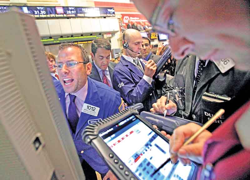 Specialist Michael Pistillo, left, calls out prices as he works at his post on the floor of the New York Stock Exchange Wednesday, July 27, 2011. (AP Photo/Richard Drew)