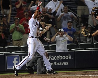 Atlanta Braves' Julio Lugo reacts to a safe call at home plate to end the game as Pittsburgh Pirates catcher Michael McKenry shows the umpire the ball during the 19th inning of a baseball game, early Wednesday, July 27, 2011. in Atlanta. Atlanta won 3-2. (AP Photo/John Amis)