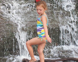 Payton Krafchek, 5-year-old granddaughter of Tom and Christine Christmas of Austintown, keeps cool at the falls near her home in Bay Village, Ohio, during the Fourth of July weekend.