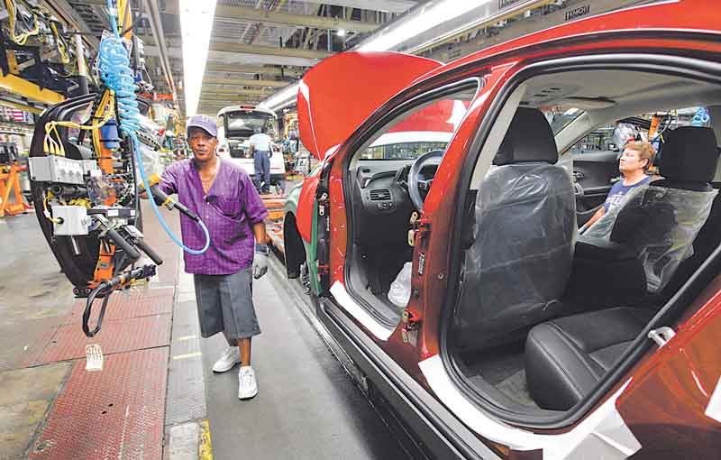In this July 27, 2011 photo, assembly line worker Edward Houie moves a door into position for a 2012 Chevrolet Volt at the General Motors Hamtramck Assembly plant in Hamtramck, Mich. General Motors Co. said Thursday, Aug. 4, 2011, its second-quarter profit nearly doubled to $2.5 billion as it got higher prices for its cars and trucks worldwide.(AP Photo/Paul Sancya)