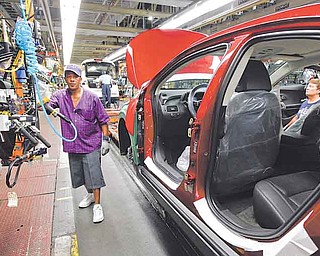 In this July 27, 2011 photo, assembly line worker Edward Houie moves a door into position for a 2012 Chevrolet Volt at the General Motors Hamtramck Assembly plant in Hamtramck, Mich. General Motors Co. said Thursday, Aug. 4, 2011, its second-quarter profit nearly doubled to $2.5 billion as it got higher prices for its cars and trucks worldwide.(AP Photo/Paul Sancya)