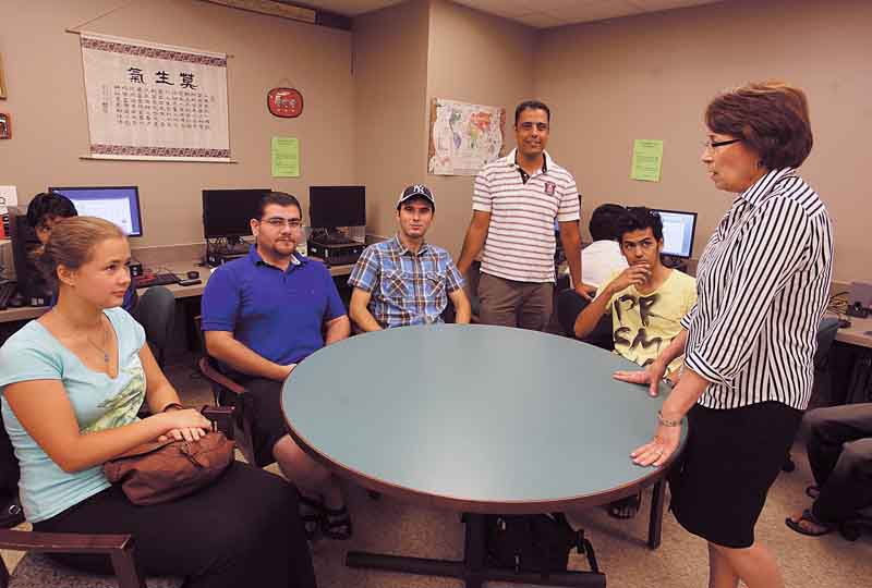 English Language Institute coordinator Lynn Greene speaks with international students, from left, Elizaveta Sadovnikova, from Russia; Amer Jaroo, from Iraq; Hiwa Hamid, from Iraq; Mansour Alsubaia, from Saudi Arabia while in the lower level of Youngstown State University’s Maag Library. Tunisian-born Wissam Abid, standing in striped shirt, provides English lessons. Along with the English Center, at 1806 Market St., Youngstown’s new immigrants rely on the two centers to sharpen their English skills.