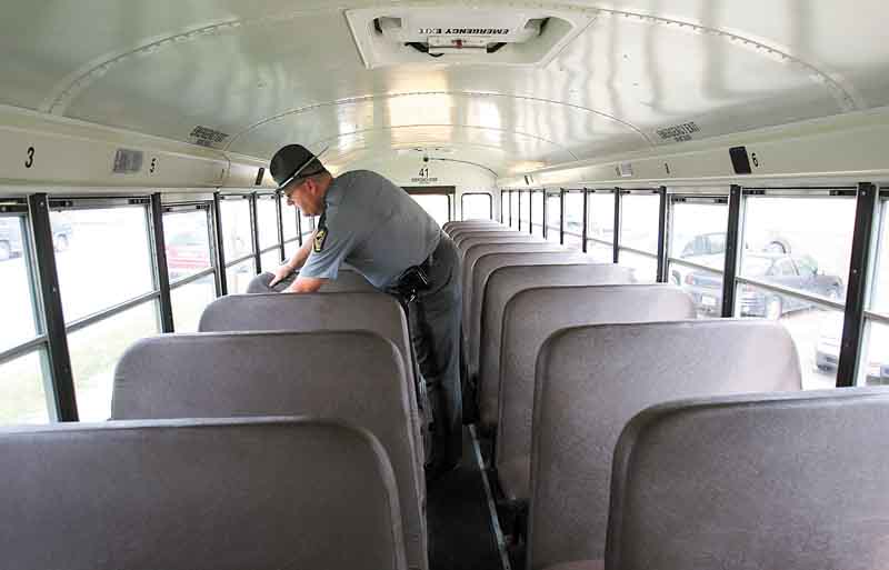 Ohio State Highway Patrol Trooper Philip Sheaffer checks the seats and windows of a Youngstown school bus. Buses don’t go on the road until they meet all parts of the inspection.  