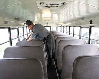 Ohio State Highway Patrol Trooper Philip Sheaffer checks the seats and windows of a Youngstown school bus. Buses don’t go on the road until they meet all parts of the inspection.  