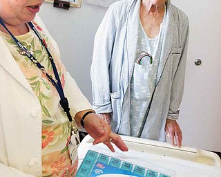 Pharmacist Joanne Heil, left, of Thomas Jefferson University Hospital, shows patient Pierre Trombert a pillbox that will help him organize his medicines at home so he won't get sick and have to come back to hospital. (Tom Avril/Philadelphia Inquirer/MCT)