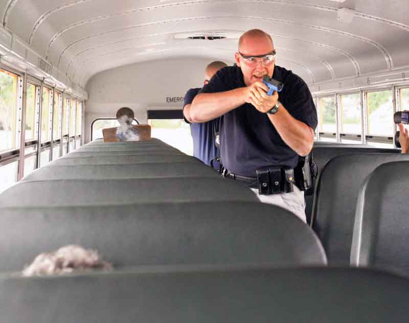 Austintown Township Patrolmen Alan Phillips and Shawn Heavner, with guns drawn, approach with a gun and knife on a school bus during a mock-crisis drill for bus drivers at Austintown Fitch High School.