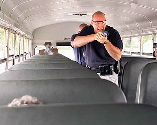 Austintown Township Patrolmen Alan Phillips and Shawn Heavner, with guns drawn, approach with a gun and knife on a school bus during a mock-crisis drill for bus drivers at Austintown Fitch High School.