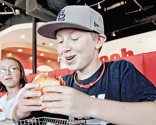 This is so good - it's thicker than most burgers, says Jeremy Hofman, 13, of O'Fallon, critiquing his first bite of his BBQ, Bacon and Cheddar Burger, his first ever burger, at Smashburger in St. Charles, Missouri, July 26, 2011. The better burger movement is sweeping through St. Louis. The latest addition is Smashburger, one of the fastest-growing chains out there, which opened its first St. Louis metro area location. His younger sister Amanda, 9, is on the left. (Laurie Skrivan/St. Louis Post-Dispatch/MCT)