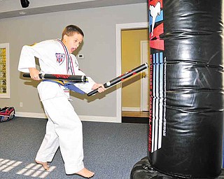 Tanner Craig, 8, of Austintown gets ready to leap into the air while striking a heavy bag at Austintown ATA Martial Arts.