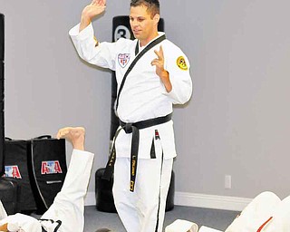 Louis Italiano leads a group of students in stretches during Monday’s class at Austintown ATA Martial Arts. ATA will host a grand opening at its new location, 420 S. Canfield-Niles Road, from 10 a.m. to 3 p.m. today.