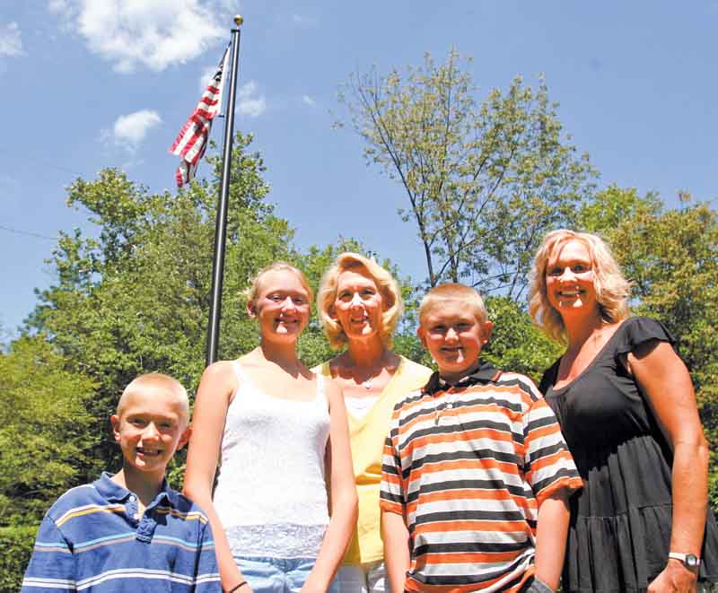 From left, Hunter Murcko, 7, Cassie Murcko, 12, and their grandmother Ruth Nilsson stand with Zachary Murcko, 11, and Amy Nilsson, in front of a flag pole memorial to Ruth’s late husband, Gary, at Pioneer Pavilion in Mill Creek MetroParks.