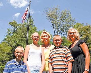 From left, Hunter Murcko, 7, Cassie Murcko, 12, and their grandmother Ruth Nilsson stand with Zachary Murcko, 11, and Amy Nilsson, in front of a flag pole memorial to Ruth’s late husband, Gary, at Pioneer Pavilion in Mill Creek MetroParks.