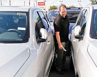 In this Aug. 11, 2011 photo, Jason Ashton looks at a new 2012 Dodge Durango at a dealership in Warren, Mich. Ashton, 38, of Shelby Township, Mich., plans to trade in his 2006 Dodge Ram pickup for a roomier SUV that will fit his wife, two kids and equipment. (AP Photo/Paul Sancya)