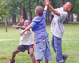 From left, Chris Vancobb, 8, Keondre Lewis, 8, and J’Alfred Clarett, 9, toss a football around at the ENOUGH picnic, an event that brought together families of victims of violent crime.