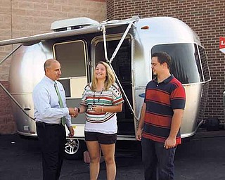 Rick Monaco, left, regional sales manager for Little Debbie Foods, hands the keys to the Airstream Trailer in the background to Jessica Clifford of Niles, who won it in a contest  sponsored by the snack food company. At right during Tuesday’s ceremony was Clifford’s fiance, Cory Diles of Braceville.