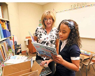 Kiara Pagan, a fourth-grader at Taft Elementary School in Youngstown, checks out some of the new books Laura Sullivan, the school’s literacy coordinator, brought for the students. Kiara enjoys reading and says she’s happy to be back in school. Monday was the first day of classes for city students.