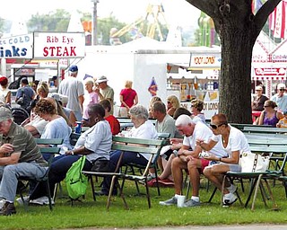 Fairgoers find a shaded area to take a break at the 165th edition of the Canfield Fair, where they can watch others, figure out which concession stand has the best food, or haggle over which attraction to attend. The fair runs today through Labor Day.