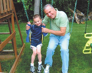 Ron Schutz is playing on the swing set with his grandson, Scottie Eaton, on Father's Day this year. Both live in Canfield.