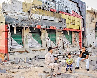 Abdul Basr, 45, center, chats with his neighbor as he sits in front of his damaged pizzeria on Tripoli Street in Misrata, Libya, on Friday.