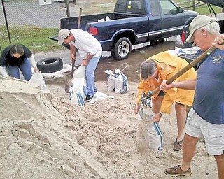 James White, right, helps fi ll sandbags with James Lewis at the Harrison County Road Department in Gulfport, Miss., on Friday. Also pictured, from left, Teresa Norman and Glenn Cunningham. Jackson County, one of Mississippi’s three coastal counties, declared a state of emergency Friday morning because of a tropical weather system in the Gulf of Mexico.
