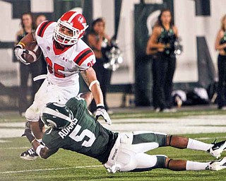 Youngstown State’s Jamaine Cook (35) tries to elude Michigan State defender Johnny Adams (5) during the Penguins’ season opener Friday in Lansing, Mich. YSU fell to the Spartans, 28-6.