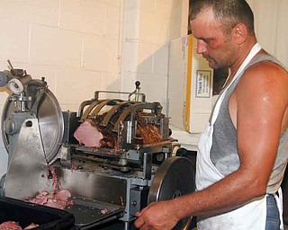 OX ROAST - Jamie Loza of Mesopotamia cuts beef for the ox roast and car show Saturday morning. - Special to The Vindicator/Nick Mays