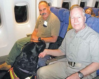 Paul Dostie, left, a retired investigator with the Mammoth Lake, Calif., Police Department, Buster, the cadaver dog he trained, and Dr. Donald K. Allen of Youngstown, are shown on their way to Tarawa, an atoll in the Pacific Ocean, to look for the remains of Americans declared missing in action in the battle with the Japanese in November 1943.