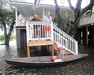 Ernie Adams sits in his pirogue while visiting his neighbors, Justin and Peggy Hatty, above, as they watch workers sandbag floodwaters from Bayou Barataria, seen in background, in the aftermath of Tropical Storm Lee in the town of Jean Lafitte, La., just outside New Orleans, Saturday, Sept. 3, 2011. (AP Photo/Gerald Herbert)