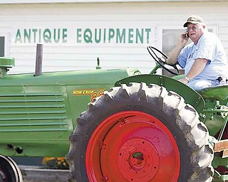 Earl Moracco of Ellsworth takes a break to make a phone call from atop his 1951 restored Oliver tractor in the antique farm-equipment exhibit at the 165th Canfield Fair.