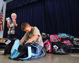 Watson Elementary third-graders Logan Swain, left, and Gage Nush check out what’s inside their new bookbags. The bookbags were donated by United Way and will be given to more than 50 students at the school.