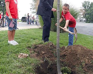 Boardman police officer Bill Woods and his children, Elena, left, and Jacob, plant a red maple tree at Stadium Drive Elementary School in Boardman as part of a Sept. 11 commemoration. Elena, a second-grader, and Jacob, a third-grader, were among the Boardman students, police, firefighters and the Boardman Band who planted trees and placed flags to mark the event.