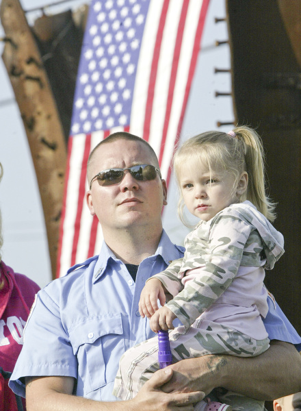 William D. Lewis | The Vindicator Austintown Fire Fighter Nick Reed holds his daughter Ariana, 3, during a Sunday observance of the 9/11 attacks at the Austintown 9/11 Memorial Park. Hundreds of area residents and representatives from many fire departments where on hand for the event.